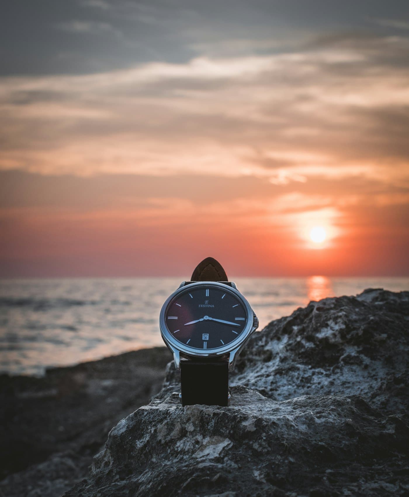 A traveller checking a Meridian watch against an open coastline at dusk